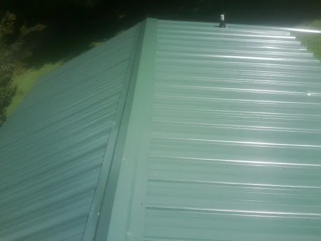 New green metal panels meeting at the ridge of a roof — Flat Roof Repair work by our crew in Sedona