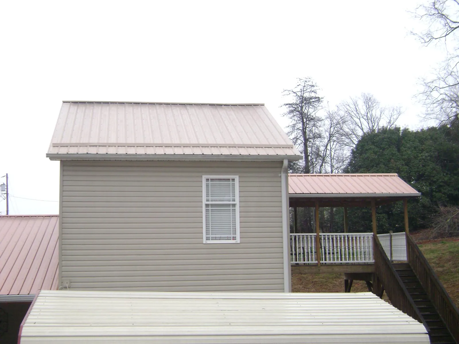 Tan metal roofs on a two story addition and attached porch, from a Roof Replacement job in Sedona