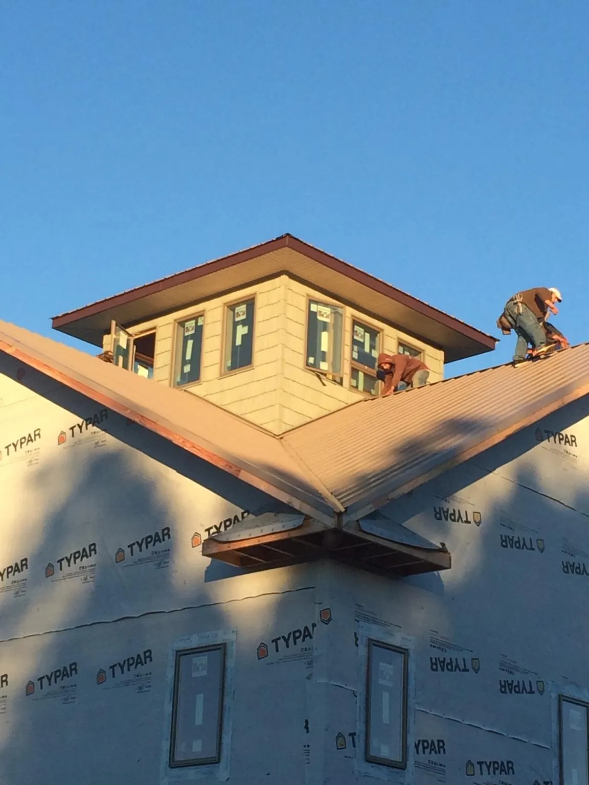 Roofers working around a rooftop cupola on a new metal roof at sunset — Roof Waterproofing in Sedona by Roofing Brothers